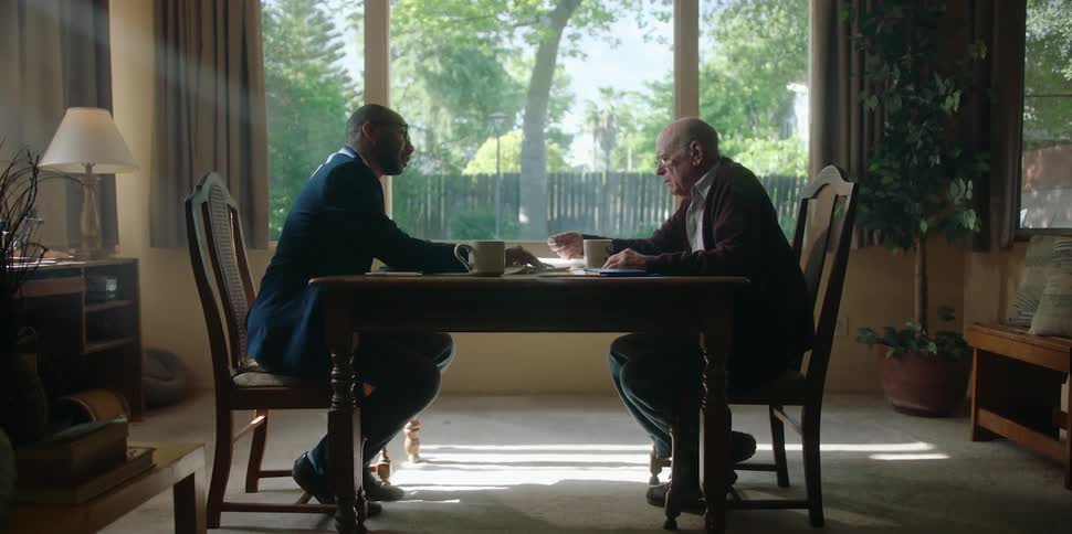 Two men talk across a table and the oldest of them gets angry