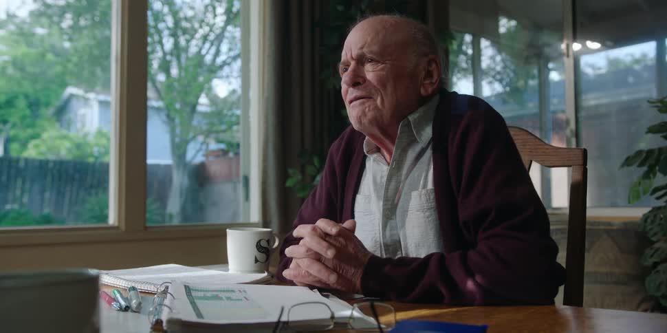 A man chats with someone while sitting at his kitchen table