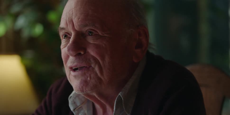 A man speaks animatedly while sitting at a table