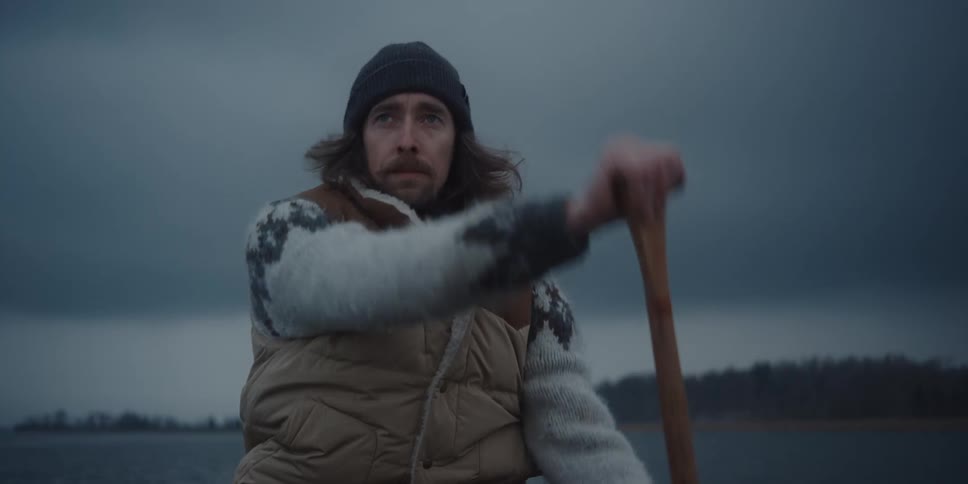 A man in a lake paddles with an oar