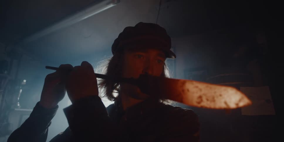 A man is holding a tool and standing in a garage