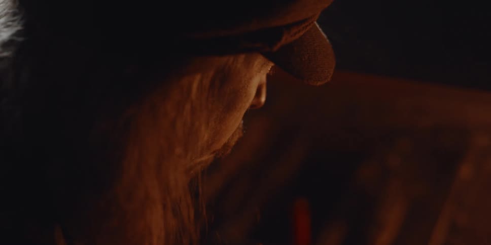 A man with long hair and beard by firelight