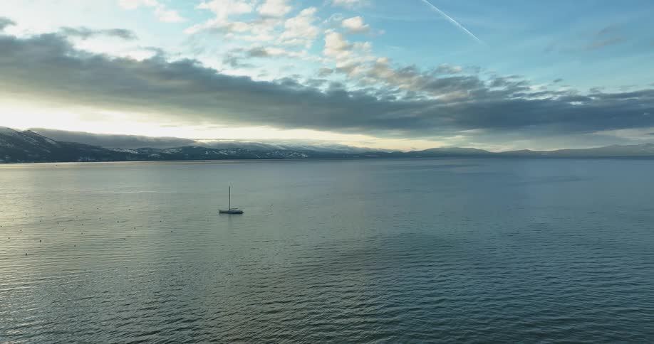 Aerial view of boat sailing on the ocean water at sunset off the coast