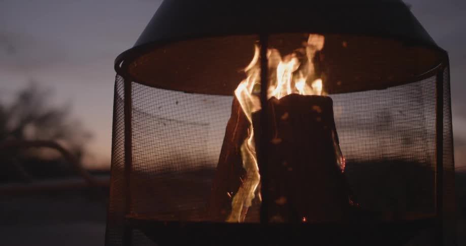 Logs burn in a fire pit at dusk
