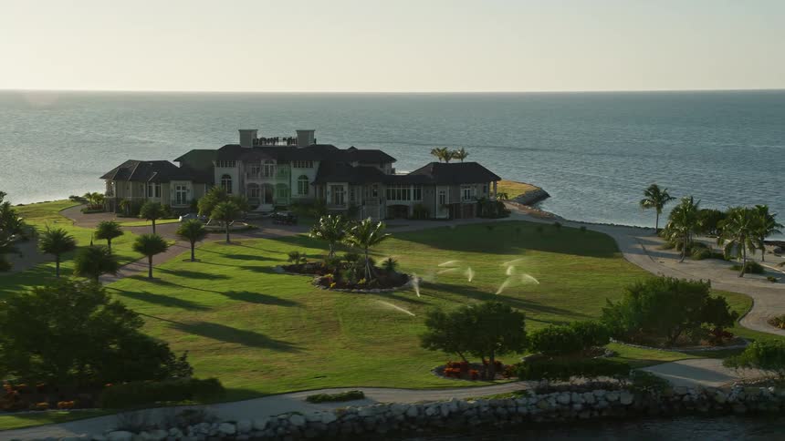 Aerial view of a rustic mansion with a sprawling estate on the shoreline of Marathon Florida during sunset