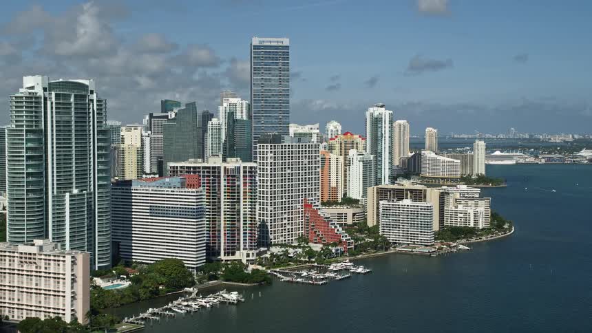 Flying above high-rise condos and skyscrapers along the shore near Four Seasons showcasing a bustling metropolis and scenic coastline in downtown Miami Florida