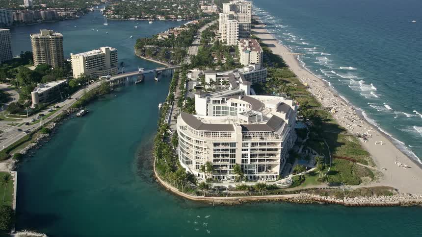 Approaching Boca Raton condominium complex with a half circle in the middle situated on the inlet to Lake Boca Raton during a partly cloudy day in Florida