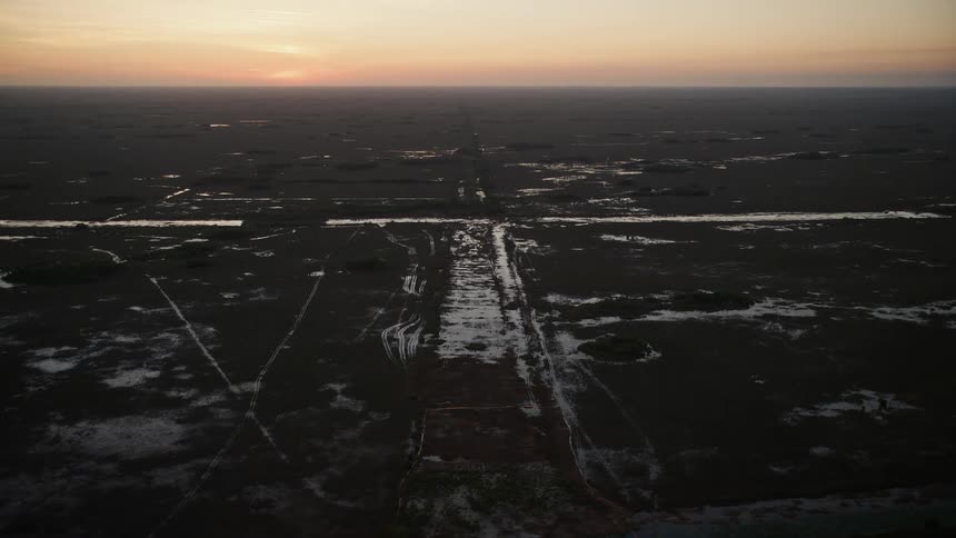 Aerial stock footage flying over Southern Glades wetlands in Florida during twilight with partly cloudy skies