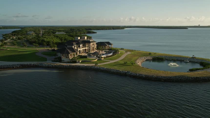 This aerial footage captures a rustic mansion located on the shoreline of Marathon Florida during dusk with an orbiting view