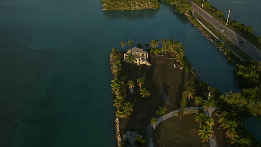 A breathtaking aerial view of a luxurious waterfront mansion on an artificial island during sunset in Craig Key Florida