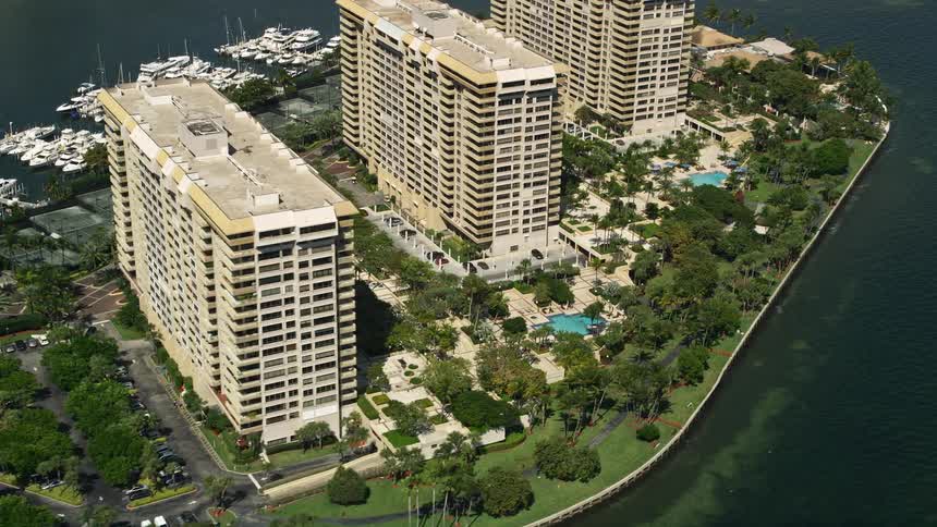 Aerial footage flying over condo complexes with pools in Grove Isle Florida on a sunny day