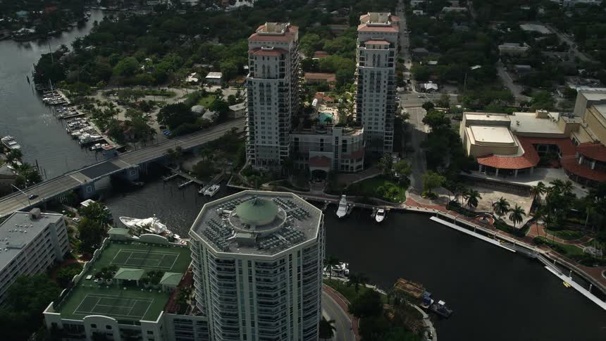 Aerial footage of Downtown Fort Lauderdale Florida as the camera approaches a condominium complex near the New River on a partly cloudy day
