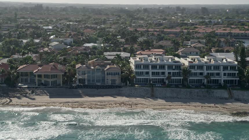 An aerial flyby of mansions and a condominium complex on the beach in Highland Beach Florida