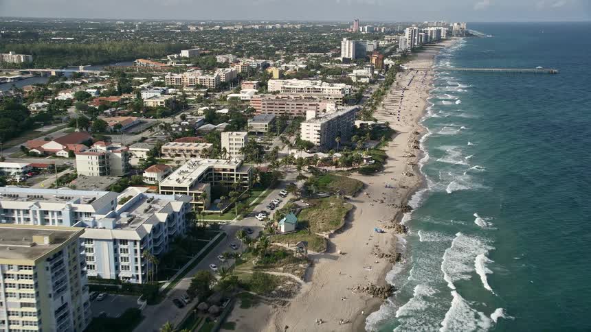 An aerial video of approaching Deerfield Beach pier and recreational activities along the coastline shot in Florida during the daytime
