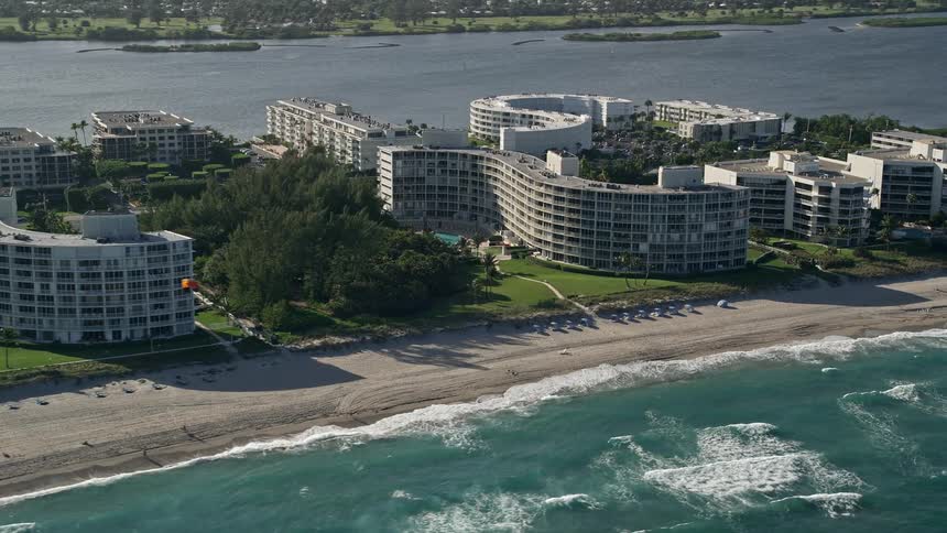Flying over a Palm Beach condominium complex on the coast with a shoreline full of sunbathers and beachgoers