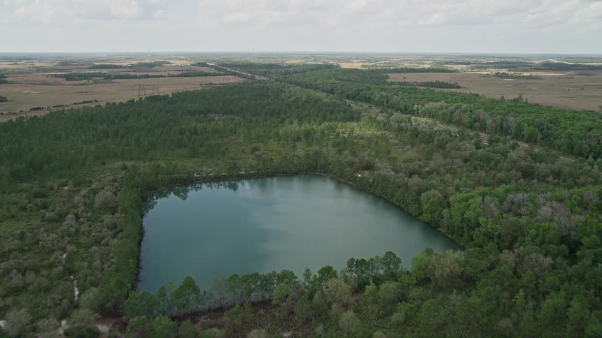 An aerial view of a forest and a lake with a highway intersecting in La Belle Florida