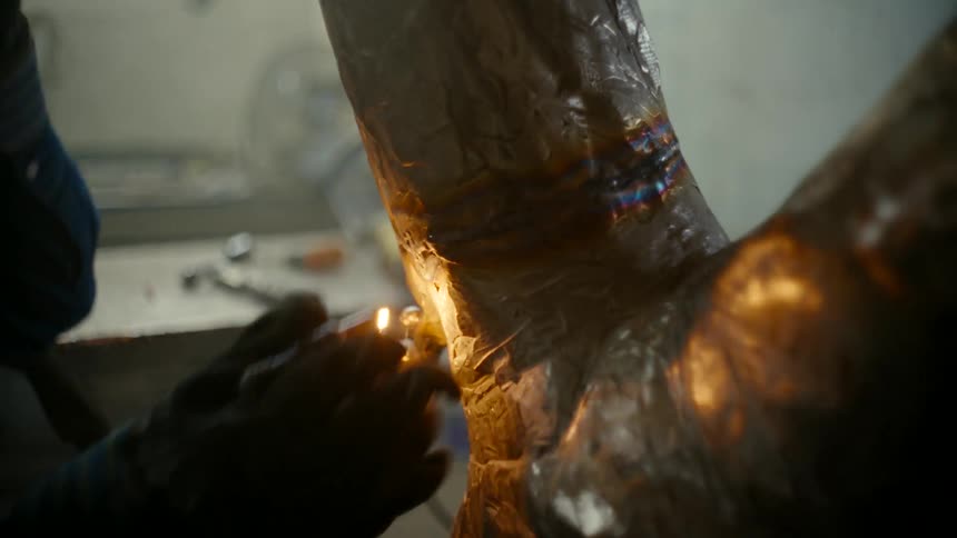 Close up of a welder welding large pieces of metal in his workshop