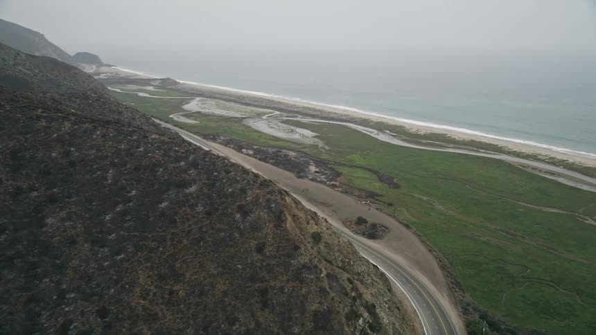 An aerial video clip of light traffic driving along Californias Highway 1 approaching the ocean and Point Mugu