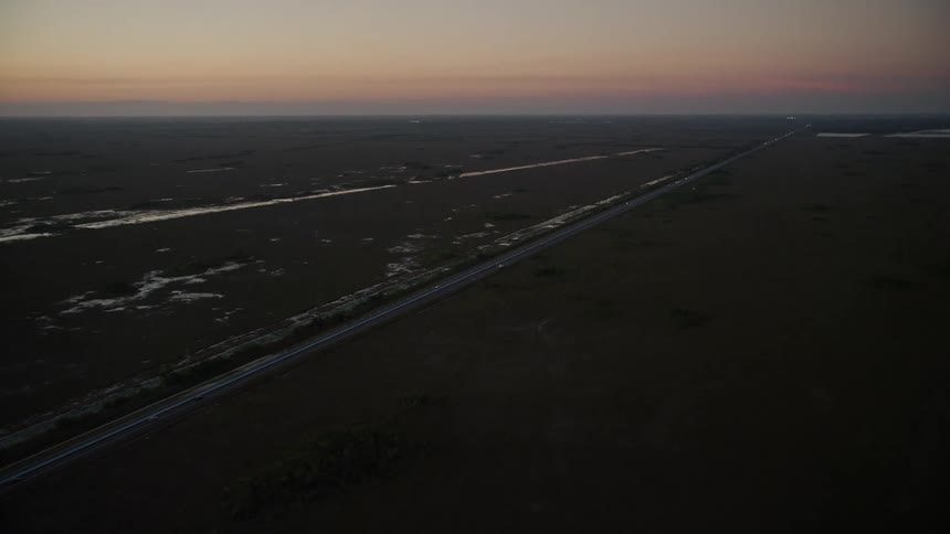 An aerial view of a car driving on South Dixie Highway through the wetlands and countryside of Southern Glades Florida during twilight