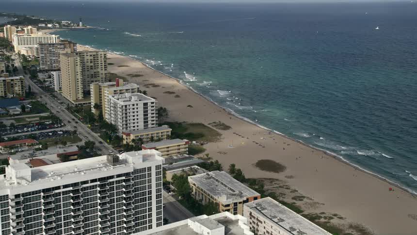 Approaching Pompano Beach through partly cloudy skies revealing the historic Hillsboro Inlet Light and condo residences on the shoreline