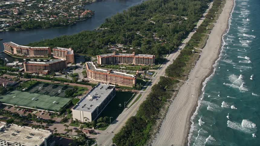 Aerial footage of orbiting a condo complex along the coast of Boca Raton FL on a partly cloudy day during summer