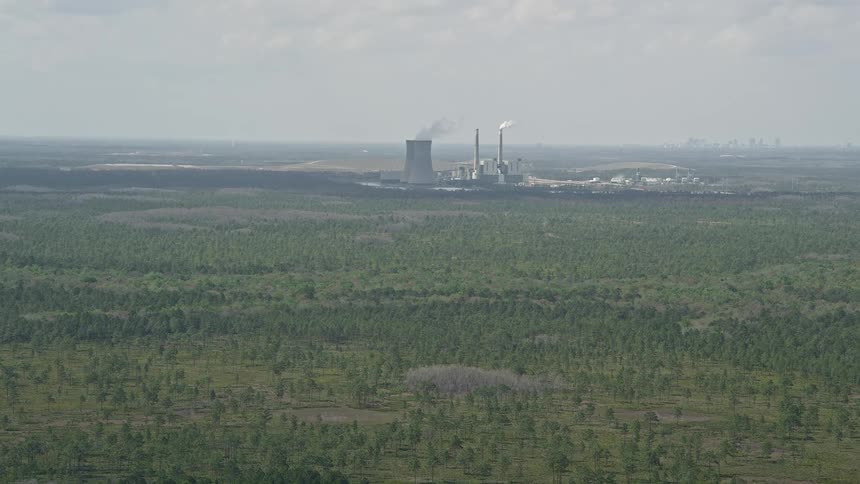 Approaching a coal-fired power generation facility in Orlando Florida on a partly cloudy day showing the polluting effects of fossil fuel energy