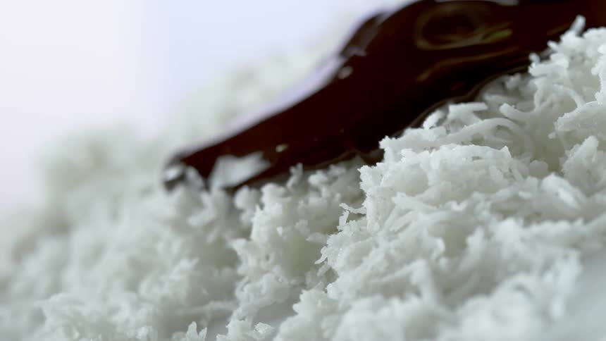 Chocolate syrup pouring over shredded coconut