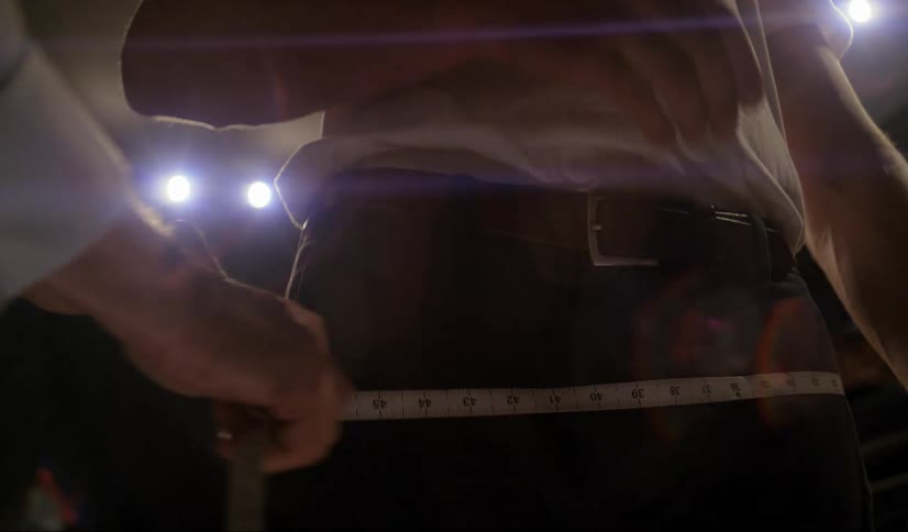 A tailor uses a tape measure to take measurements of the clients waist