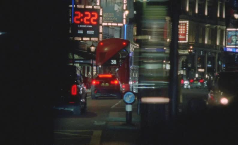 Vehicles and pedestrians throng busy road in city at night in London