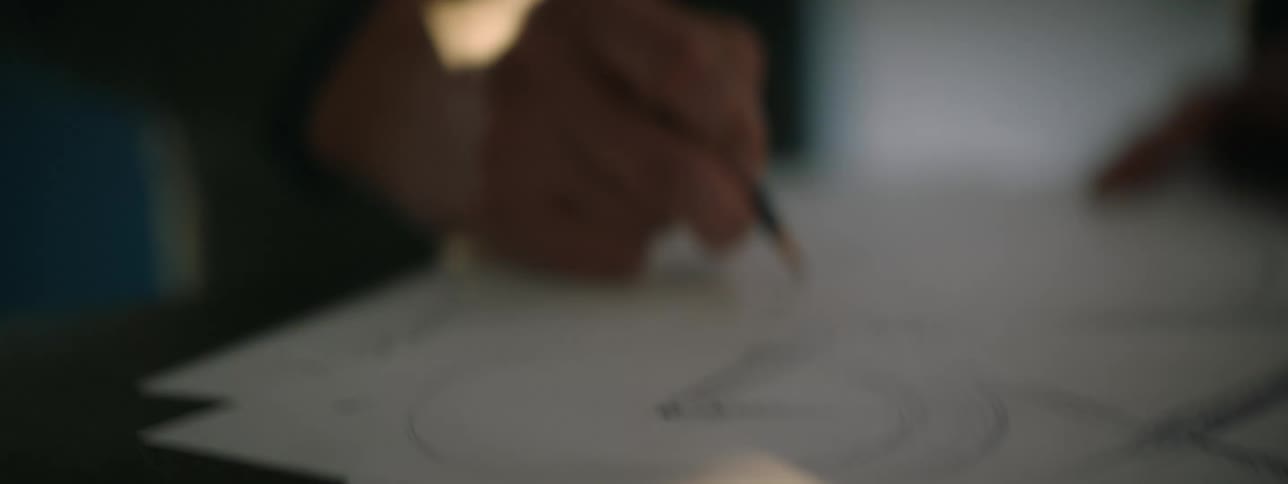 A closeup shot of a man sketching a design by hand onto paper
