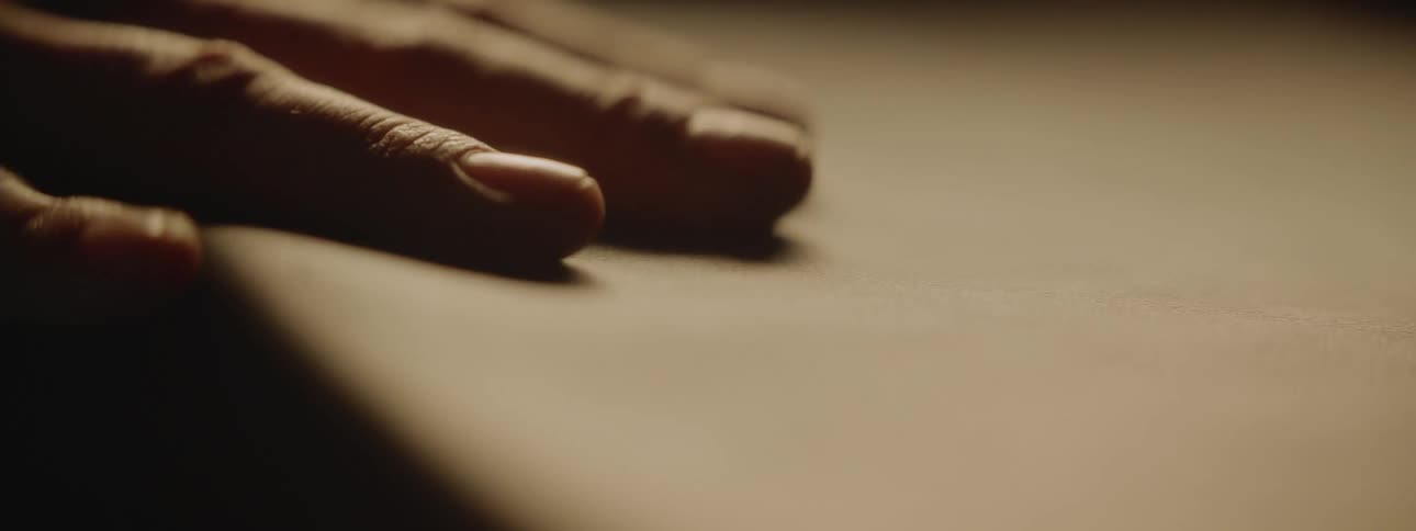 A person runs their hand along the surface of a table