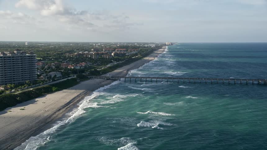 An aerial view of Juno Beachs pier and shoreline during a sunny summer day