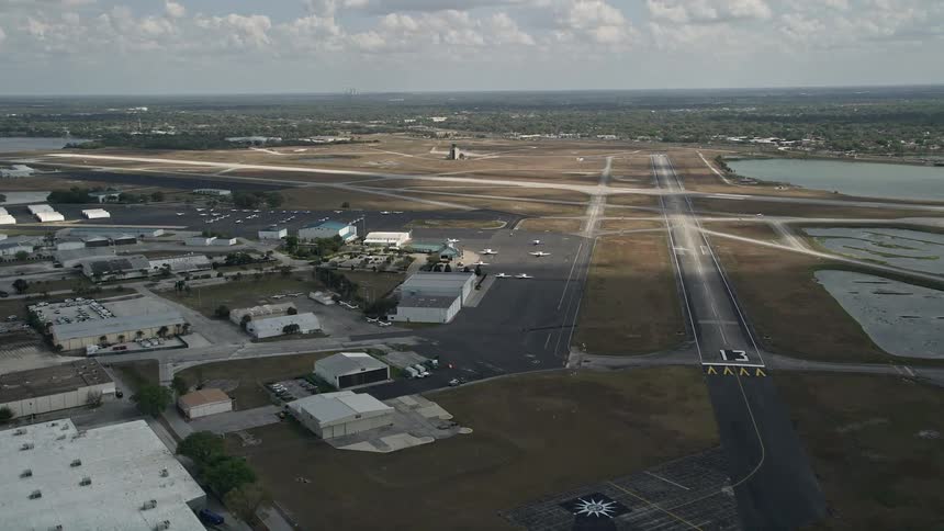 Flying over Orlando Executive Airport in Florida showcasing planes parked on the tarmac and small airfields in partly cloudy skies