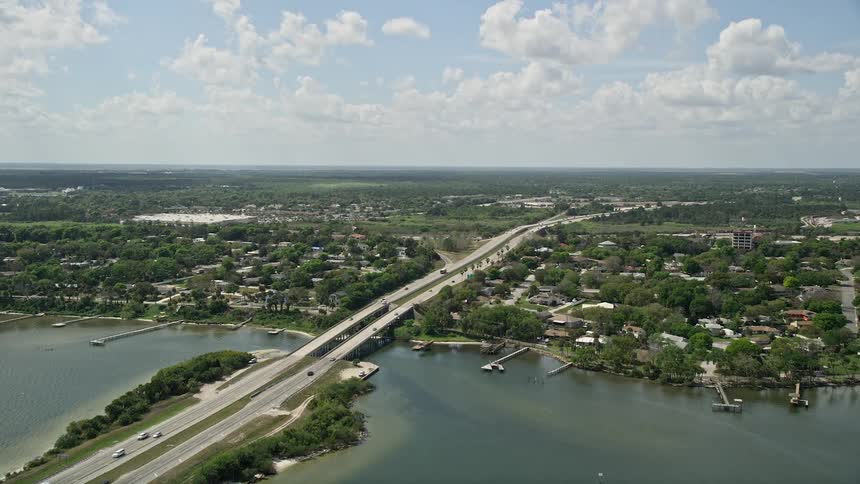 Aerial footage panning over a causeway in Cocoa Florida revealing residential neighborhoods and a bridge leading to a wide open landscape