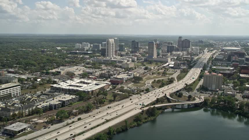 Aerial view of Downtown Orlando skyline and Interstate 4 during the daytime with partly cloudy skies and an approaching 