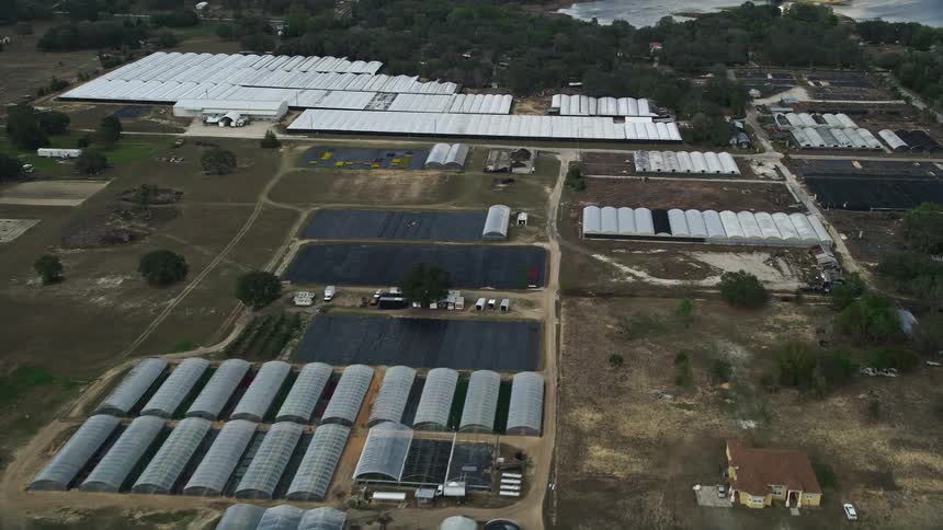 Approaching greenhouses at a Florida farm from an aerial during daytime in partly cloudy skies