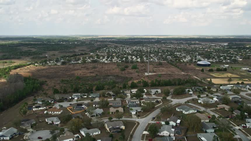 An aerial view of Clermont Florida showcases residential neighborhoods and swamps on a partly cloudy day
