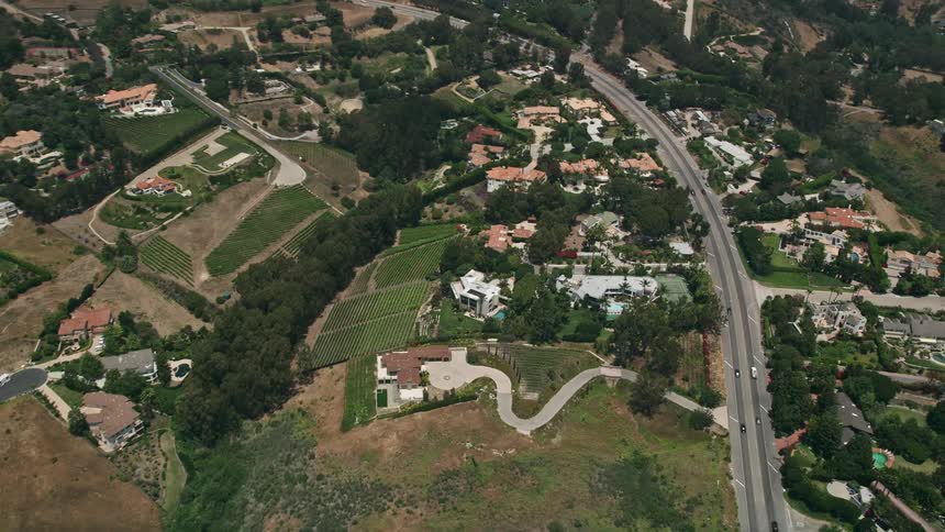 An aerial birds eye view of sprawling mansions and vineyards in the hills of Malibu California on a hazy day