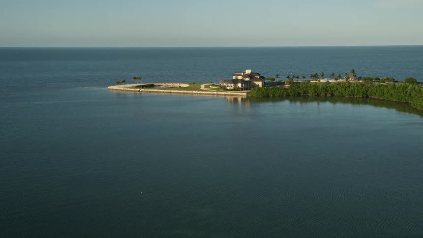 Aerial footage of a luxury mansion on a headland near the coast of Marathon Florida during sunset