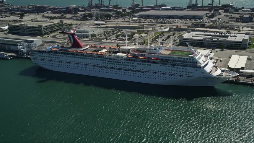 Aerial view of a Carnival Cruise Ship docked at the Port of Miami Florida near Biscayne Bay amidst sunshine and clear skies perfect for vacations and sightseeing