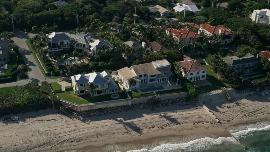 A stunning aerial flyby of upscale homes in Ocean Ridge Florida along the ocean coastline with waves crashing against the beach