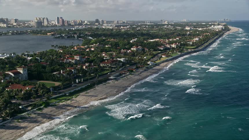 A breathtaking aerial view of upscale residential neighborhoods and luxurious mansions lining the shoreline of Palm Beach Florida