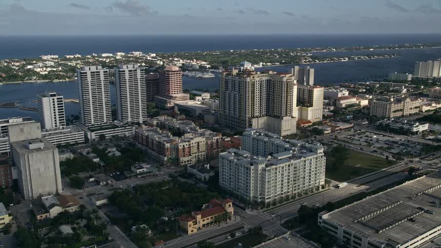 Aerial footage of flying past Trump Plaza and high-rise apartments in West Palm Beach Florida on a partly cloudy day