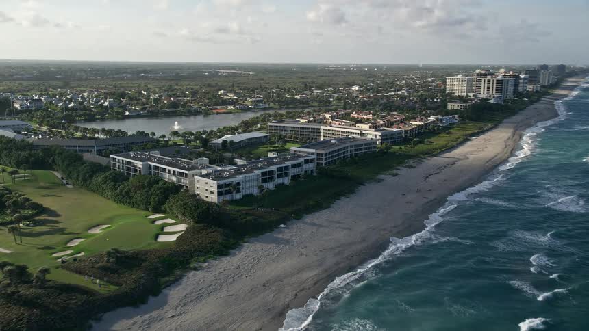 A stunning aerial view of beachfront apartment buildings along the coast in Juno Beach Florida on a partly cloudy day