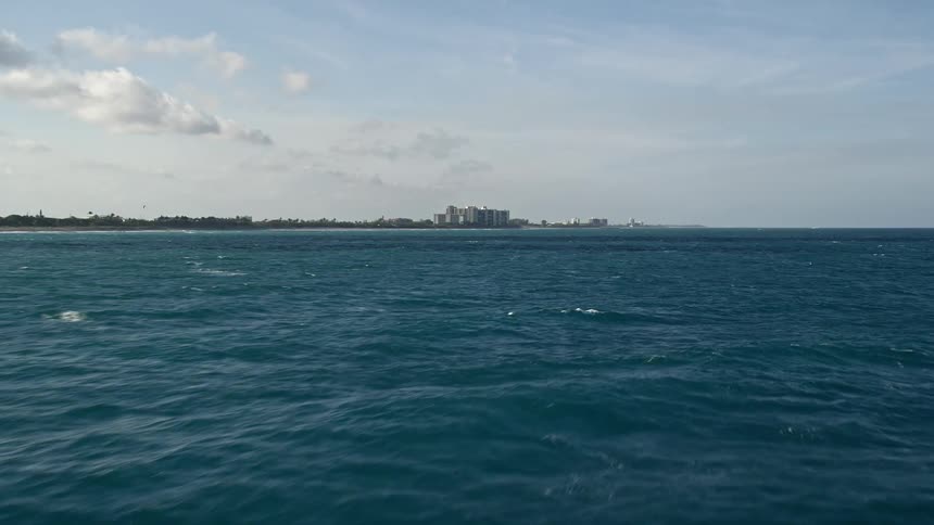 Aerial footage of approaching Floridas coastline from the Atlantic Ocean flying low with partly cloudy skies toward Jupiter in Palm Beach County during summer
