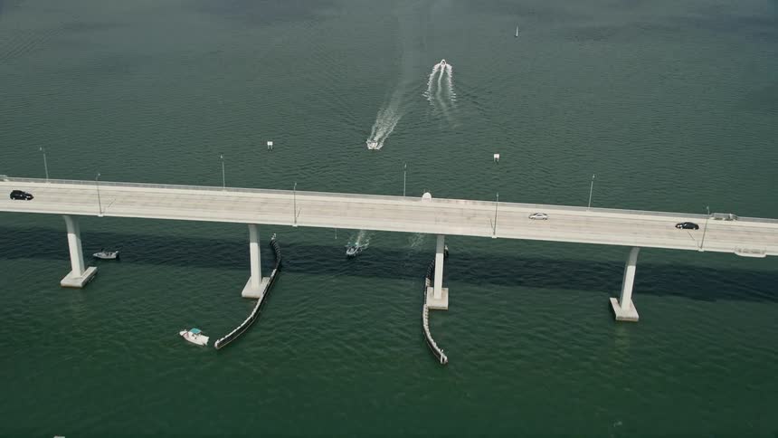 Several speedboats approach and pass under a large bridge on the Indian River in Stuart Florida