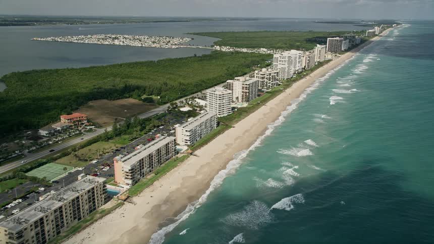 A stunning aerial view of apartment buildings on the beachfront and blue ocean waters in Jensen Beach Florida