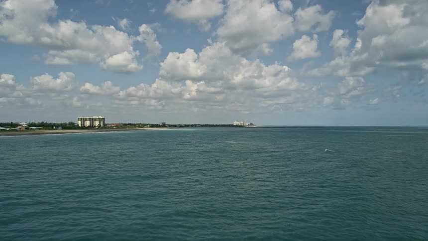 A low flying aerial camera captures the beautiful coastline of Fort Pierce Florida as it approaches a distant beach with a building