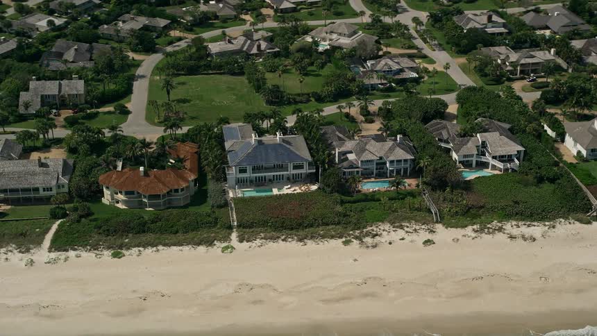 An aerial view of luxurious homes and mansions on the beach in a suburban neighborhood with pools in the front yard taken from a drone in Vero Beach Florida during the summer