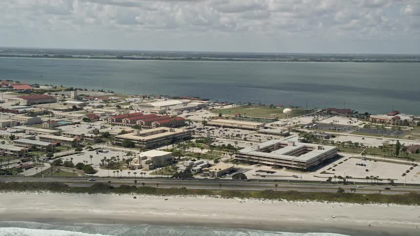 Aerial footage of Patrick Air Force Base buildings and vehicles moving along the highway during a partly cloudy day